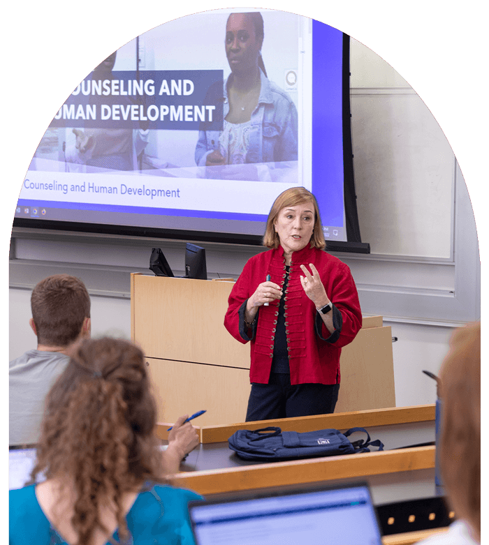 GSEHD faculty member speaks to class, presentation behind her labeled counseling and human development