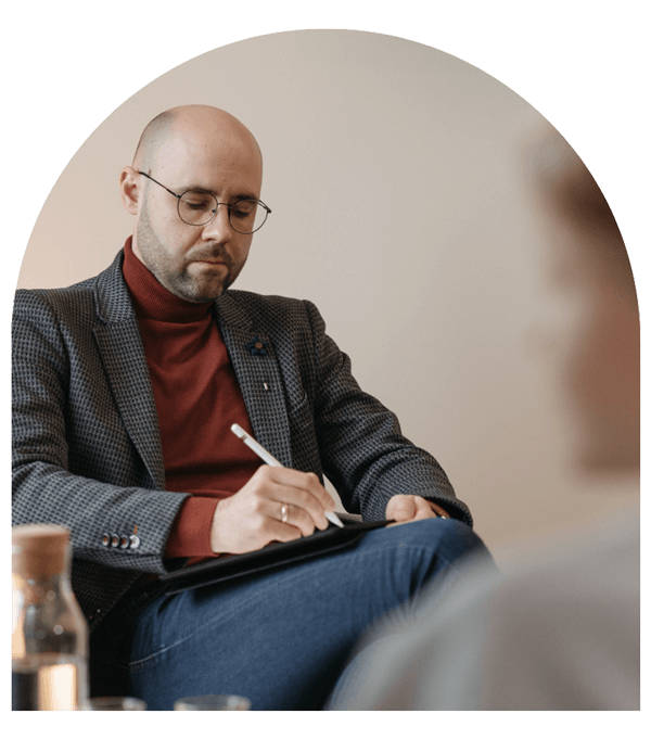 male counselor takes notes on notepad while talking to client