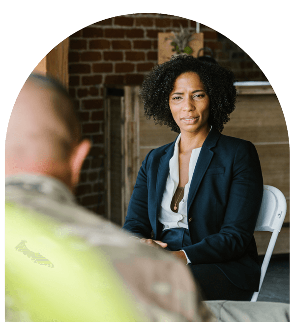 female counselor listens while speaking to client dressed in military clothing